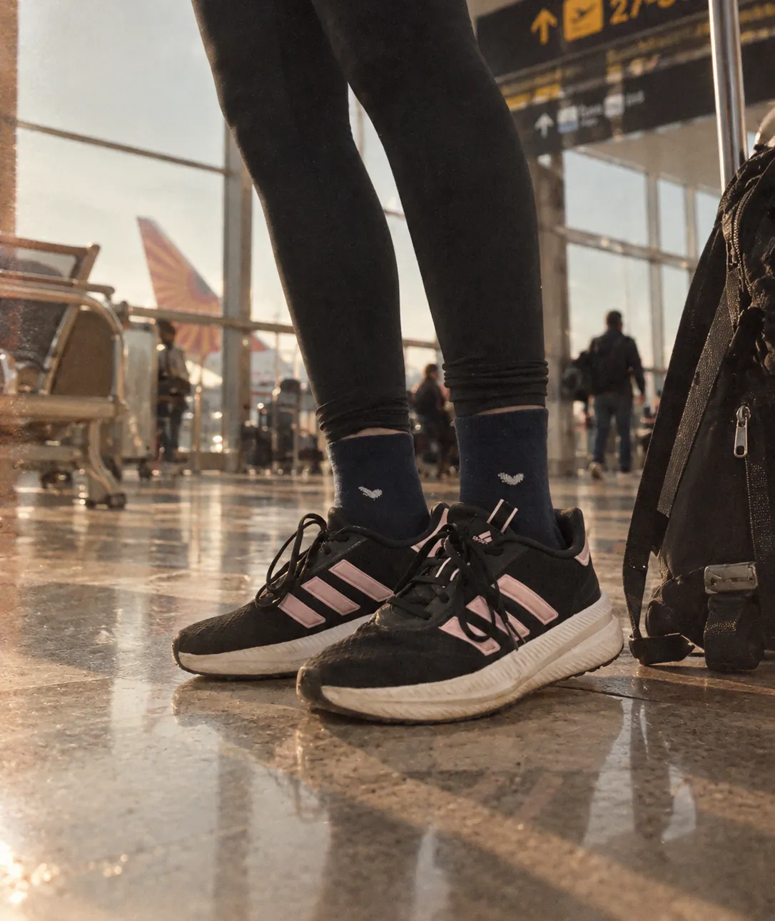 Navy socks worn with black trainers in an airport terminal