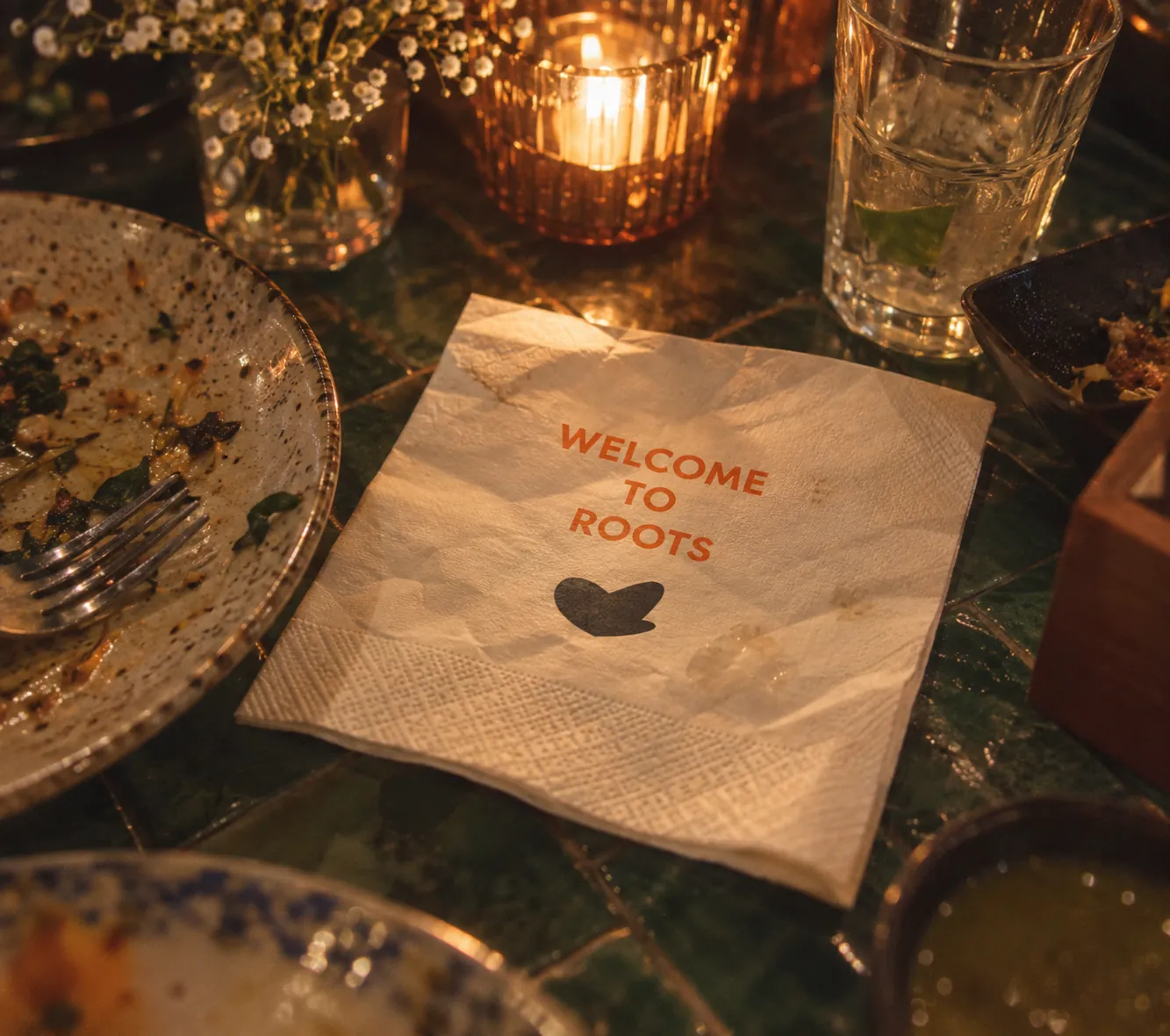 A napkin printed “Welcome to Roots” beside a cleared plate