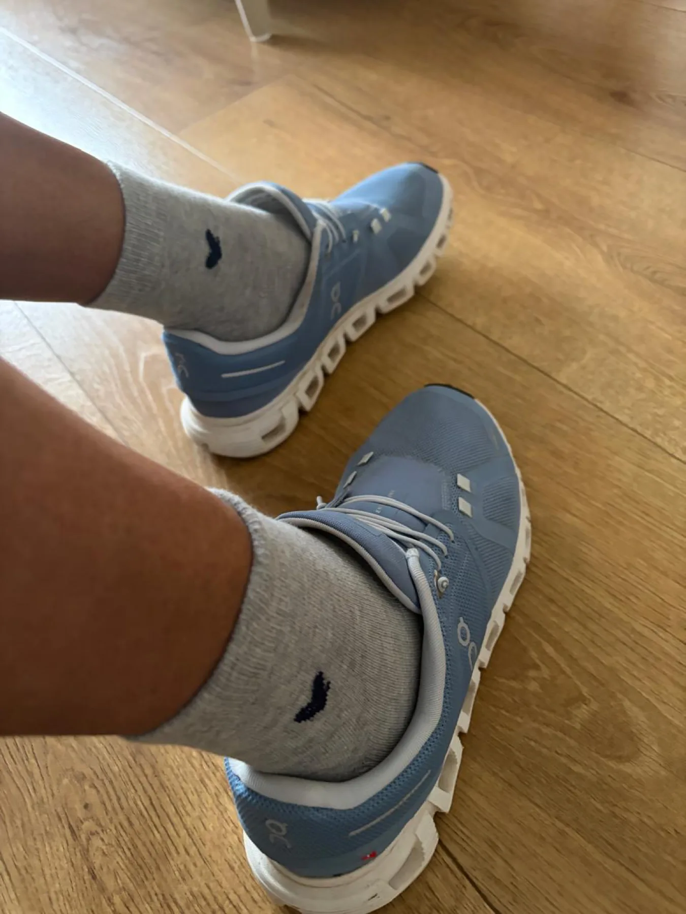 Basalt Grey worn with blue trainers on a wooden floor