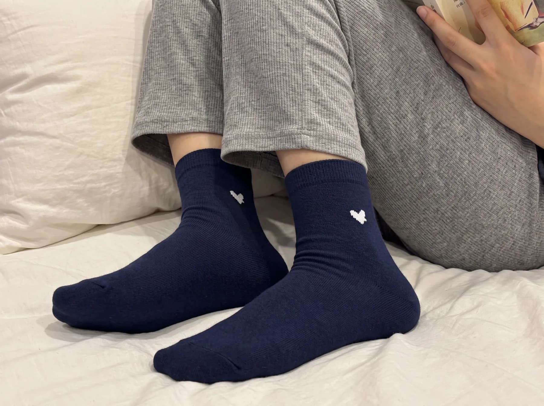 Vesper Navy in the crew length, resting on white bed linen