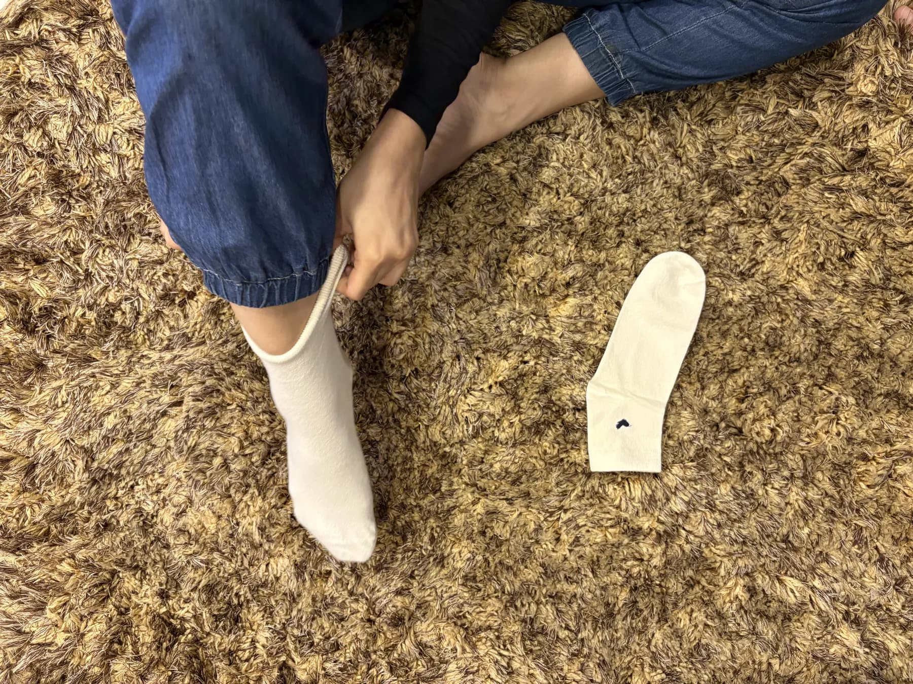 Pulling on a pair of Vesper Oat on a soft rug